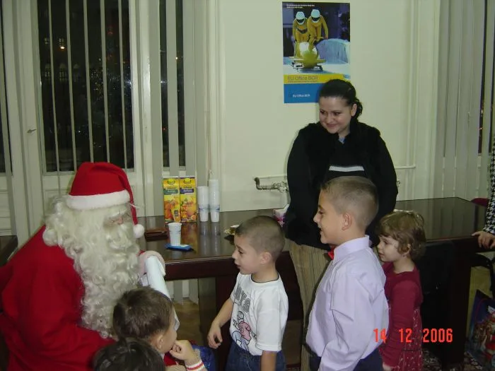 Moș Crăciun împărțind daruri copiilor la un eveniment de firmă